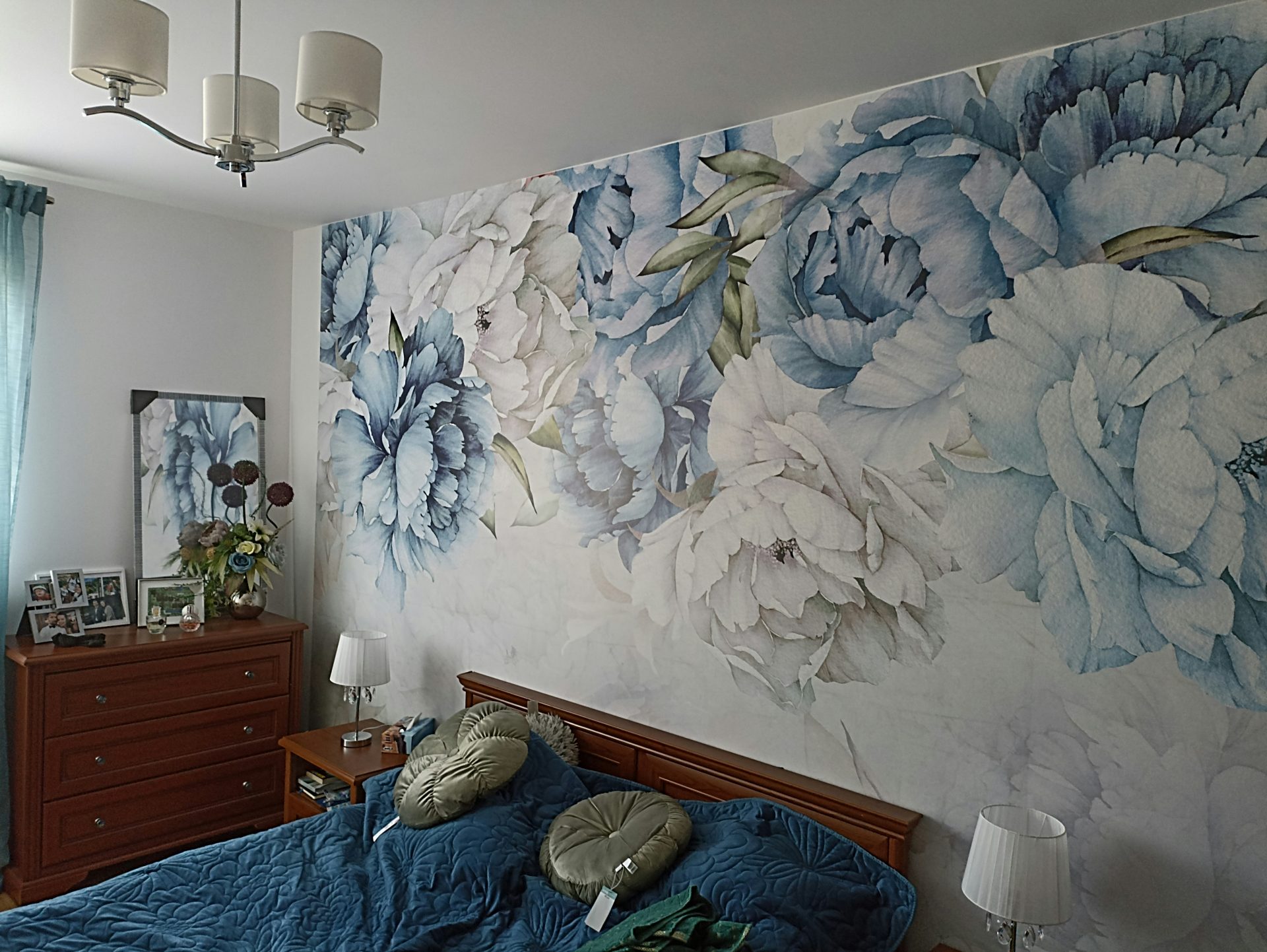 a bed room with a neatly made bed and a painting on the wall